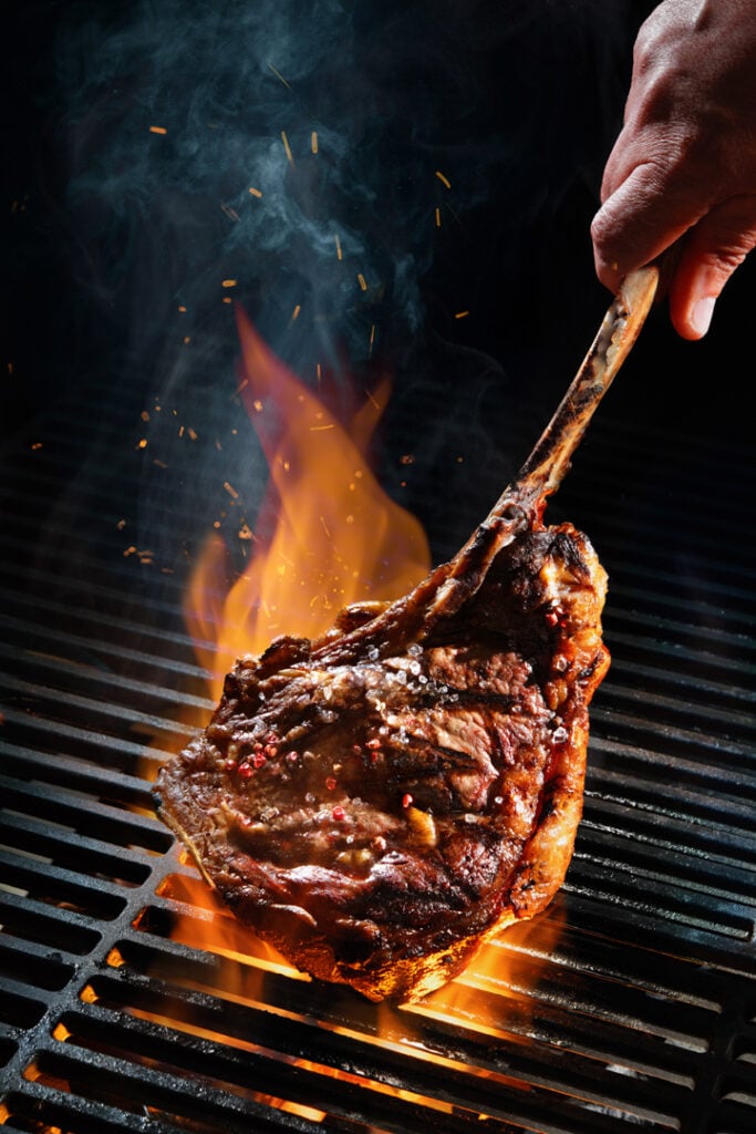 Beef steak on the grill with smoke and flames